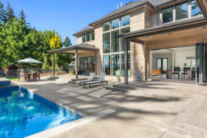 Luxury home exterior and pool on sunny day with blue sky