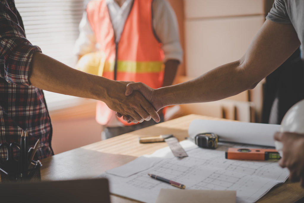 A homeowner shaking hands with a home remodeler before a construction project takes place